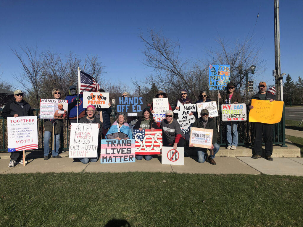 A group of protesters from Western Wayne Indivisible holding a variety of signs supporting American democracy.