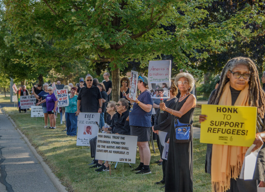 A line of people hold pro-immigrant signs at an interfaith vigil, Sept. 17, 2025.