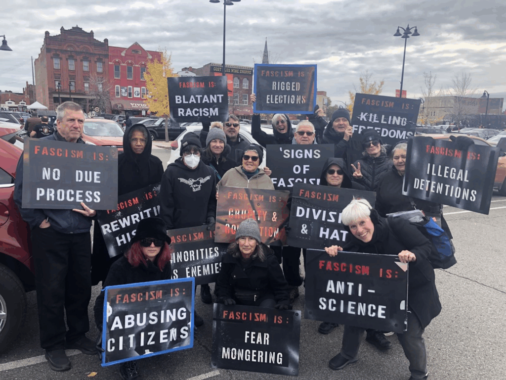 A group of people holding signs showing the signs of fascism